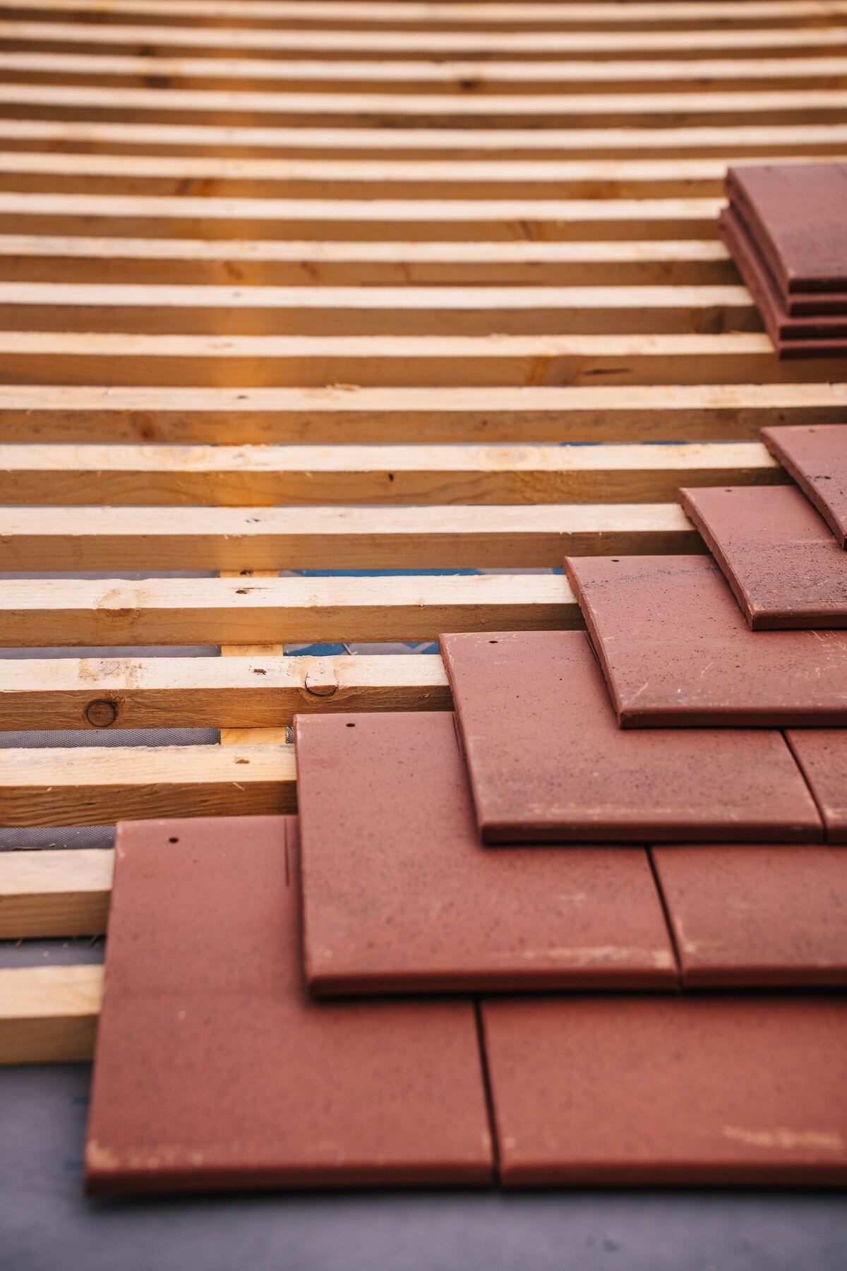 Rode dakpannen liggen klaar op de houten panlatten